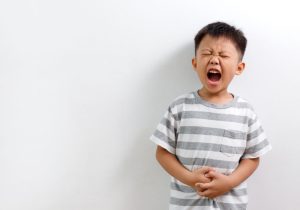 Little Asian boy having abdominal pain, isolated on white background.